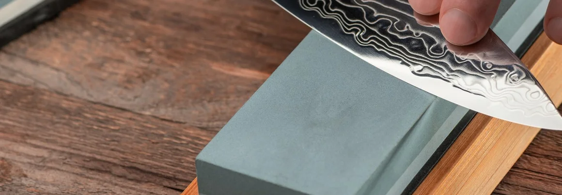 Person schärft Messer mit Schleifstein